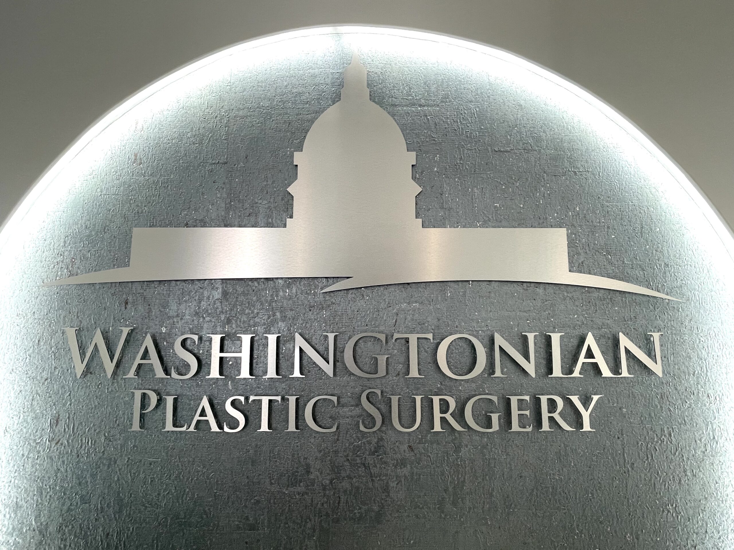 Washingtonian Plastic Surgery reception desk and illuminated logo wall in McLean, Virginia